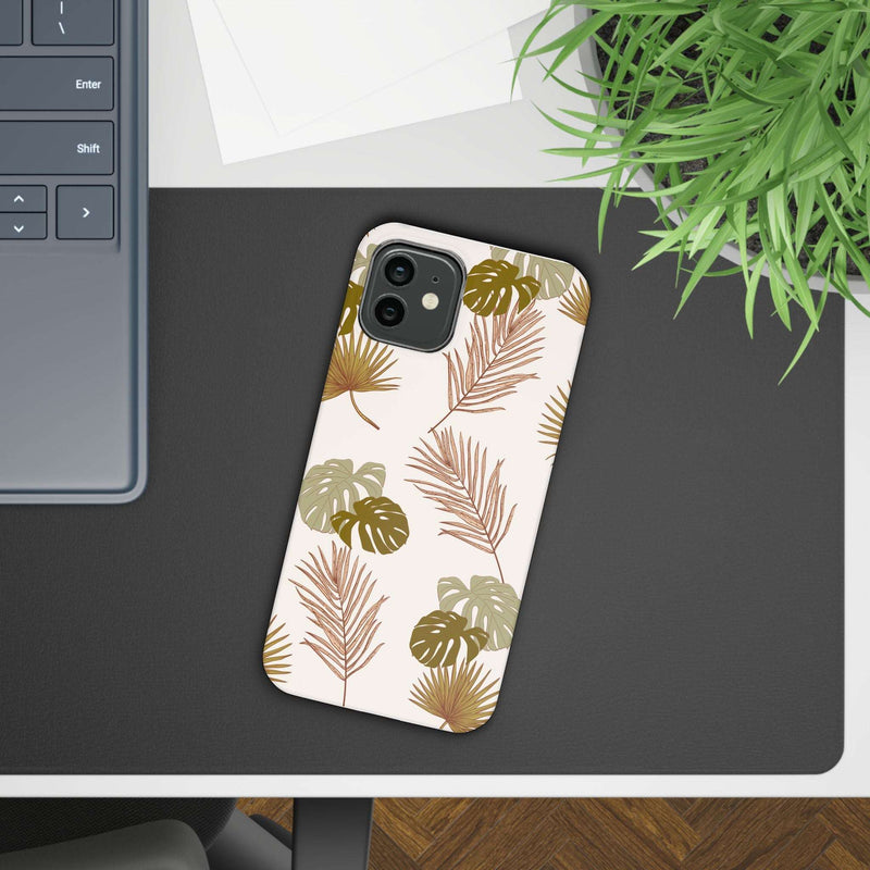 Nature-inspired mobile phone case with tropical leaf design on a desk next to a plant and keyboard.