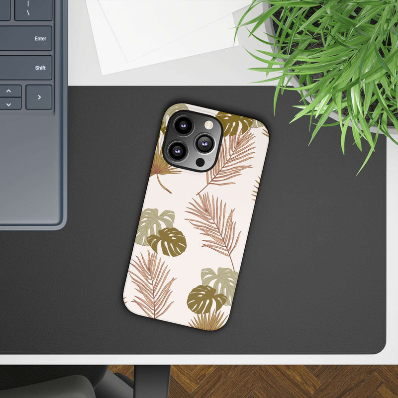 Nature-inspired mobile phone case with tropical leaf design on a desk next to a laptop.