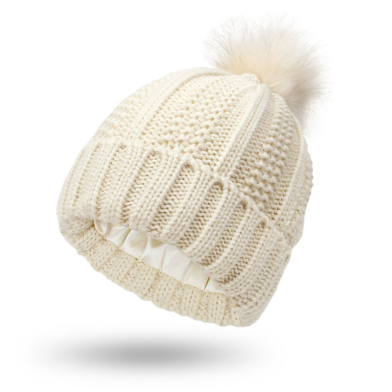 Satin-lined beanie with faux fur pom pom for winter warmth and style.