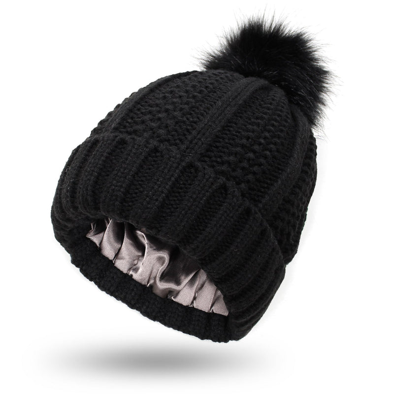 Satin-lined beanie with faux fur pom pom in black, offering moisture retention and warmth.