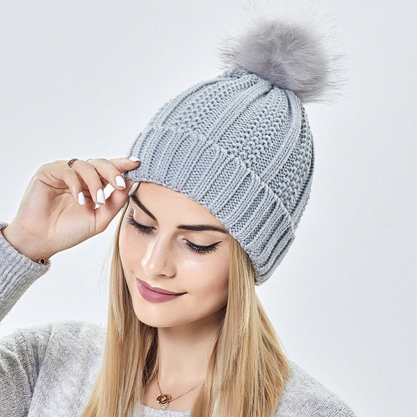 Satin-lined beanie with faux fur pom pom in light gray, featuring a knitted wool design for winter warmth and style.